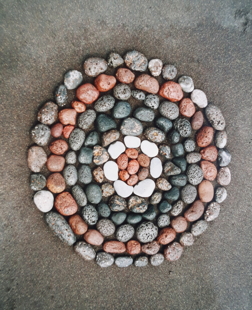 Rundes Mosaik aus bunten Steinen auf Sand
